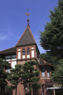 Sivri çatılı ve ağaçlı tarihi tuğla bina