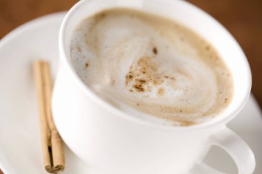 Seramik fincanda tarçınlı sıcak kahve kapuçinosu.