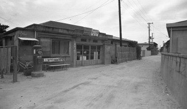 Bulutlu gökyüzünün altındaki eski ahşap binaların yanında terk edilmiş kumlu bir sokak.