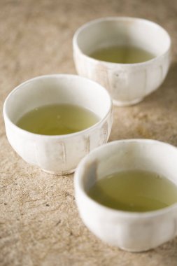İçinde sıcak yeşil çay bulunan üç seramik bardak.