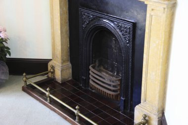 Pirinç parmaklıklar ve fayanslarla süslü siyah şömine.