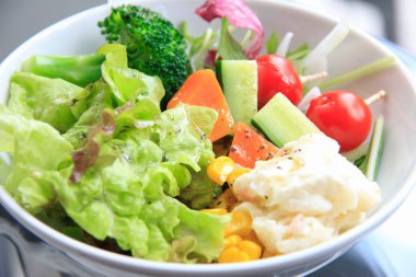 Karışık sebze salatası ve beyaz masada taze sebzeler.