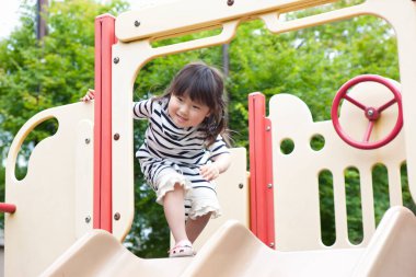 Asyalı küçük kızın portresi oyun alanında eğleniyor.