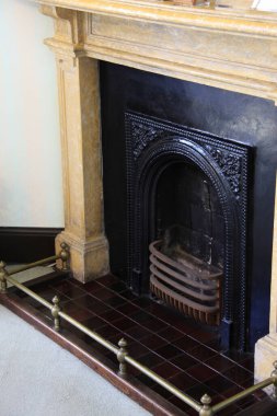 Pirinç parmaklıklar ve fayanslarla süslü siyah şömine.