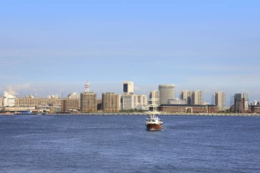 Nehirde yüzen gemi, arka planda modern şehir binaları, Tokyo, Japonya