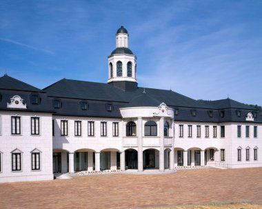 Mavi gökyüzünün altında merkezi kulesi olan büyük, zarif bir bina.