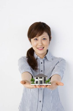 Evin minyatür bir modelini tutan genç bir kadın.