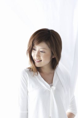 Beyaz elbiseli Asyalı kadın stüdyoda poz veriyor.