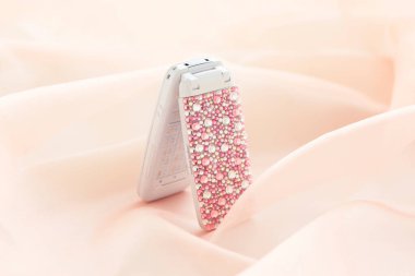 Yatağın üzerinde pembe kristallerle süslenmiş bir telefon..