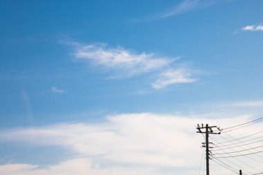 Mavi bulutlu gökyüzüne karşı elektrik kabloları