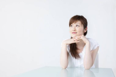 Masada oturan genç Asyalı kadın. 