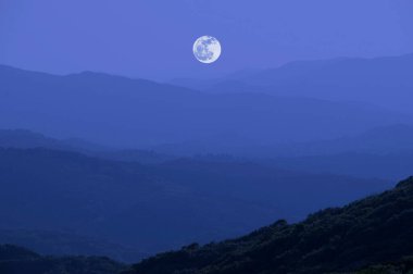 Dolunay manzaralı dağlarda koyu mavi gökyüzü   