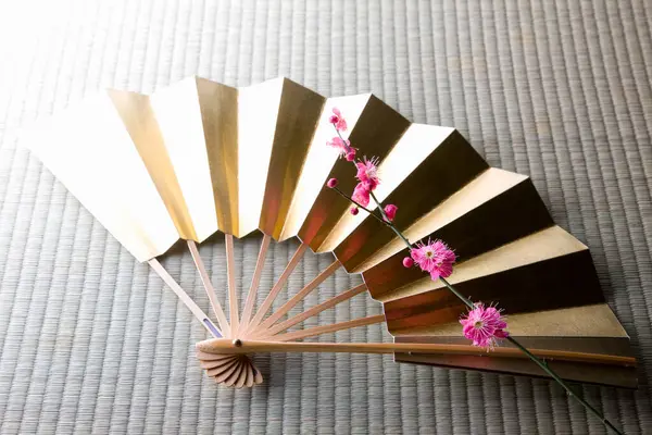 Altın Japon yelpazesi ve çiçek açmış bahar ağacının pembe çiçekleri 