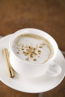 Seramik fincanda tarçınlı sıcak kahve kapuçinosu.