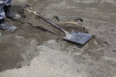 Düşük kesim işçiler ve kürek bir kum yığını üzerinde dinleniyor