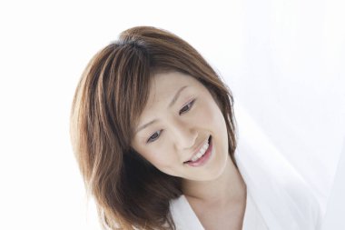 Beyaz gömlekli Asyalı kadın stüdyoda poz veriyor.