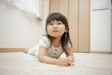 Asyalı küçük kız halıya uzanmış.