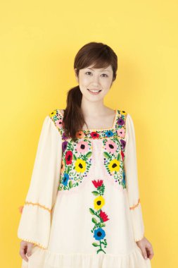 Asyalı genç kız sarı arka planda izole edilmiş. 