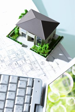 Masasında ev modeli olan modern bir dizüstü bilgisayar. Emlak sigortası kavramı