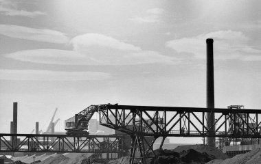 Siyah ve beyaz köprülerin ve bacaların yer aldığı sanayi manzarası