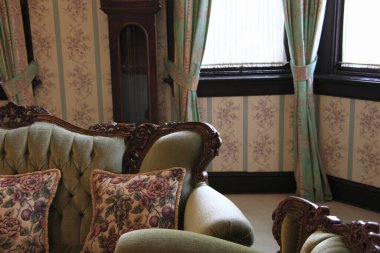 Eski moda, rahat yastıkları ve pencereyi süsleyen yeşil perdeleri olan bir kanepe.