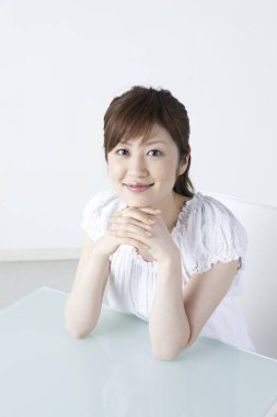 Masada oturan beyaz gömlekli genç bir kadın. 