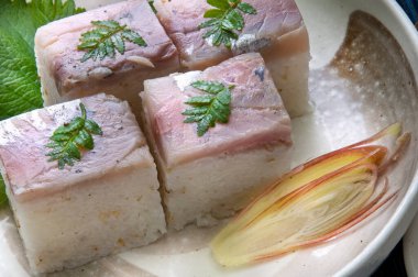 Suşi kareleri, tabakta balık ve otlarla.