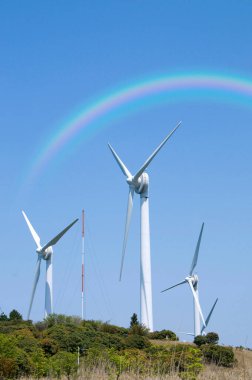 Tepede rüzgar türbinleri ve arka planda gökkuşağı. Yenilenebilir enerji kavramı