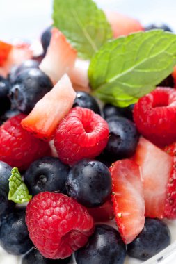 Üstünde nane yaprakları olan bir kase meyve.