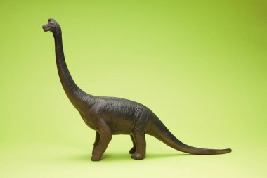 Yeşil arka planda sevimli dinozor oyuncağı                     
