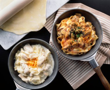 İki tavada hamurun yanında kremalı makarna tabağı var.