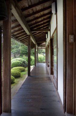 Yeşillik bahçesine bakan geleneksel binanın yanındaki ahşap geçit.