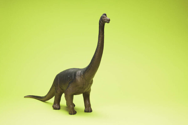 милый динозавр игрушка на зеленом фоне                     