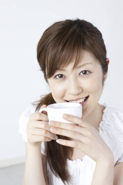 Elinde kahve tutan Asyalı kadın.