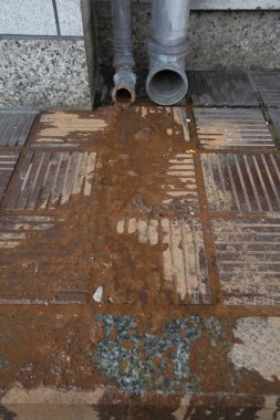 Metal boruların yakınındaki eski beton kiremitleri kaplayan paslı su lekeleri