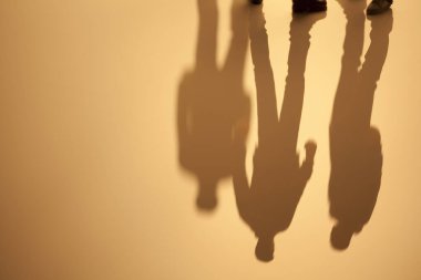 Yansıtıcı yüzeyde yürüyen üç adamın gölgeleri.