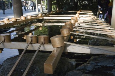 Geleneksel arıtma çeşmesinin yanında duran tahta kepçeler.