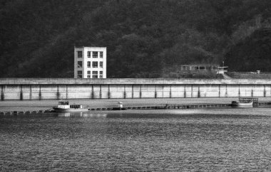 Beyaz binanın yanında uzun beton iskelenin yanında yüzen küçük tekneler.