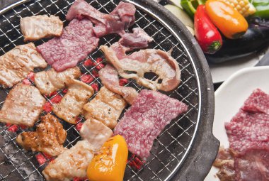 Japon restoranındaki ızgarada et ve sebze pişiren kişinin yakın çekim görüntüsü 