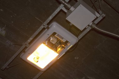 Aydınlatılmış endüstriyel tavan lambası parlak sarı parıltı yayıyor.