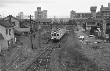 Şehir demiryolunun iyi bakımlı dış hatları yoğun bir Japon caddesine paraleldir..