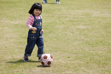 Sahada futbol oynayan genç bir kız.