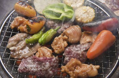 Japon restoranındaki ızgarada et ve sebze pişiren kişinin yakın çekim görüntüsü 