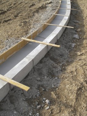 Sert toprak zemin boyunca sınır oluşturan eğri beton bloklar