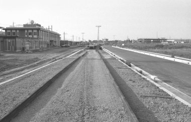 Bitmemiş binalar ve elektrik direklerinin yanında inşaat halindeki çakıl yolu.