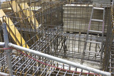 İnşaat alanı çelik inşaat iskeleti ve ahşap tahtaları gösteriyor.