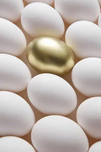 white egg and golden egg on background, close up