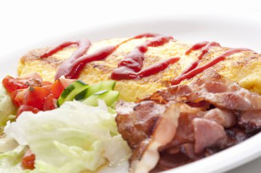 Domuz pastırması ve sebzenin yanında ketçaplı omlet.