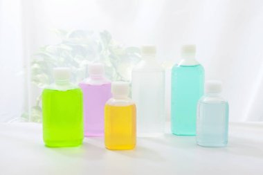 Işık arkaplanındaki renkli plastik sıvı şişelerinin yakın plan görüntüsü       