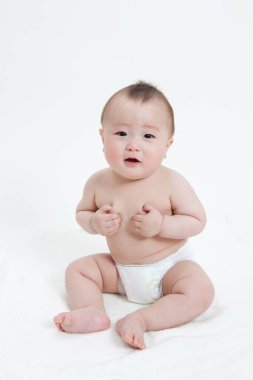 Beyaz arka planda bebek bezi takmış sevimli Asyalı bebeğin stüdyo portresi